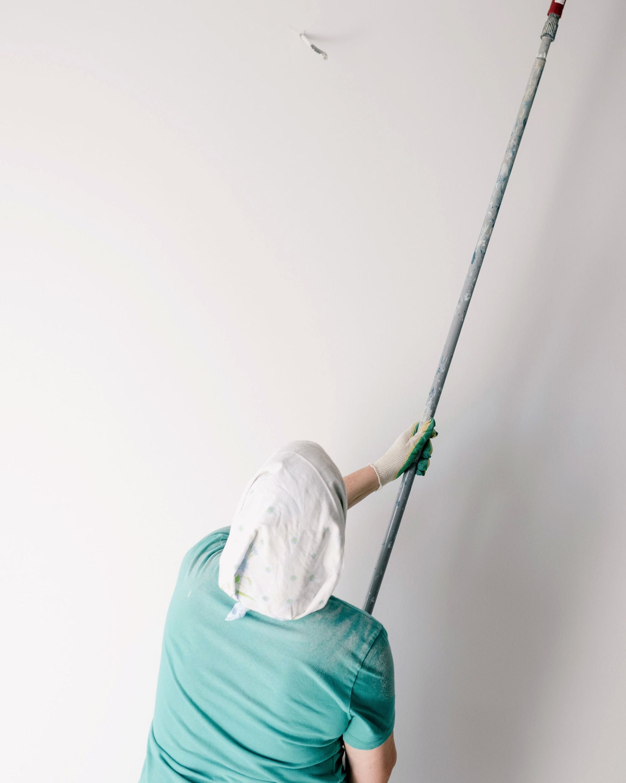 Maler von hinten mit Rolle an der Decke.